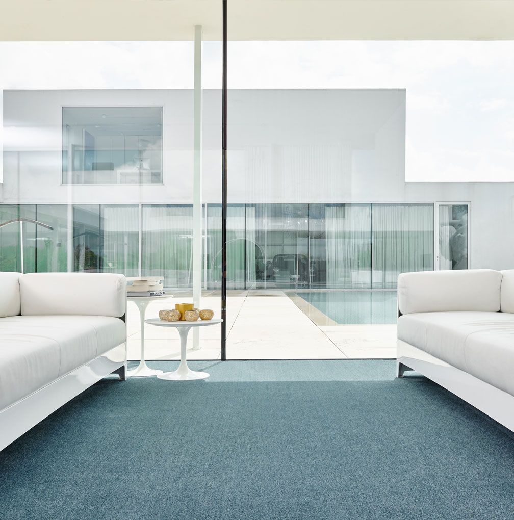 Modernes Zimmer mit blauem Teppich und weißen Möbeln